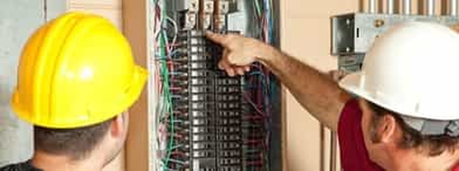 image of an electrical panel being inspected by two professional electricians prior to repair