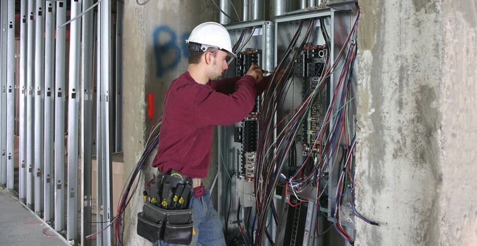 a commercial electrician working on a large circuit box at a work site in Fort Lauderdale, FL